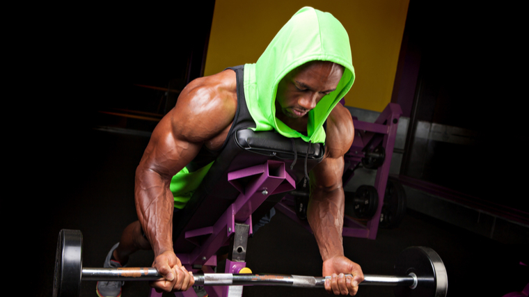 A person wears a bright green hooded tank top while performing a spider curl.