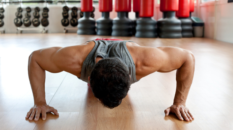 A person performs a push-up in a gym.